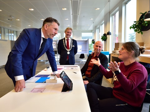 Minister Frank Rijkaart (l) vraagt aan Evelien hoe het is om op het stembureau te werken