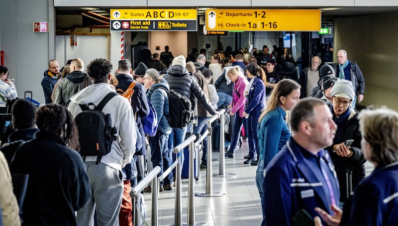 Reizigers staan dinsdag in de rij bij de servicebalie van KLM op luchthaven Schiphol. 