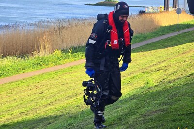 Baasje springt hond achterna het water in langs dijk in Spijkenisse