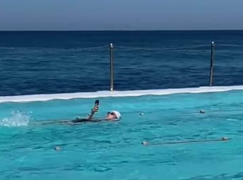 Vrouw zwemt met mobiel.