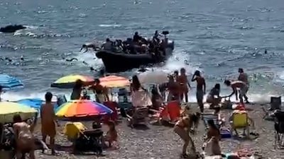 Verbazing bij strandgangers in Spanje: migranten springen voor kust uit overvolle boot en zwemmen naar strand