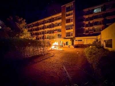 Brandweer blust brandende stapel met afval bij gekraakte Paasbergflat in Arnhem
