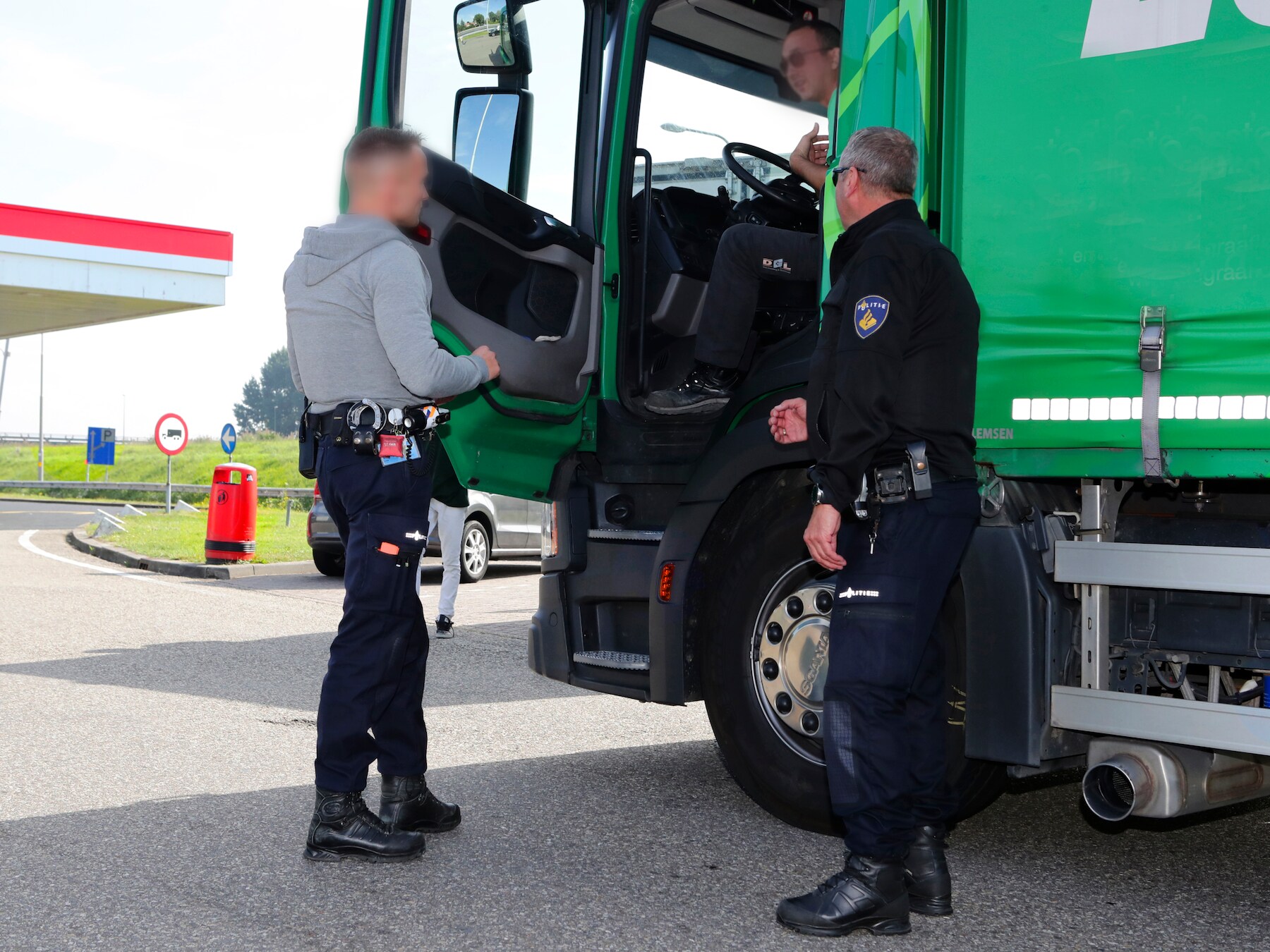 Een vrachtwagenchauffeur wordt aangesproken op het gebruik van zijn mobiele telefoon achter het stuur door een team dat met een onopvallende politieauto op de weg zit.