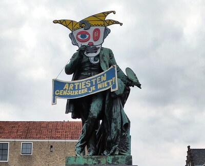 Heb jij dit protest al gespot in de binnenstad? Ary Scheffer met een narrenkop en afgeplakte mond