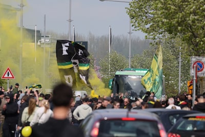 Bus van kampioen ADO Den Haag komt aan bij stadion, opgewacht door grote groep uitzinnige supporters