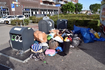 Zakken vol kleren achtergelaten naast afvalcontainers bij winkelcentrum in Zaltbommel