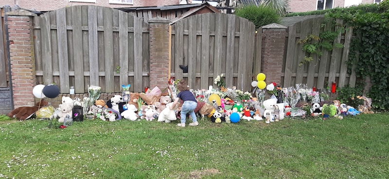 De dochter van Micky Klaassens legt een knuffel neer bij de schutting in Geleen waarachter Gino werd gevonden.