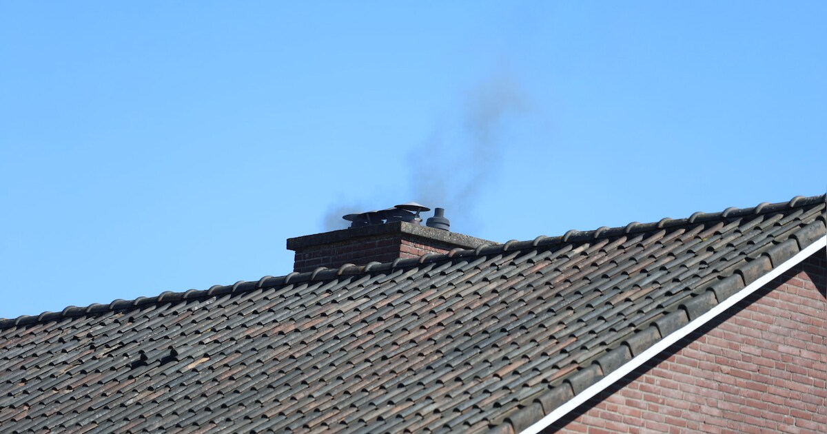 Zwarte rook uit schoorsteen van woning aan het Hopperus Bumaperk in Drachten