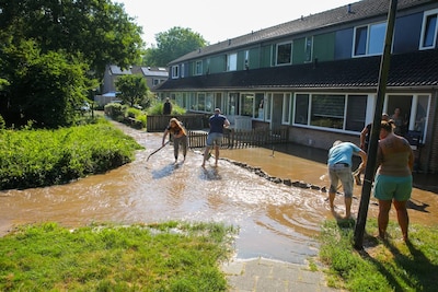 Water stroomt door straat in Apeldoorn na leidingbreuk, bewoners in de weer met zandzakken