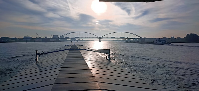 Een binnenvaartschip passeert een duwstel in de opvaart, richting Duitsland. Dit ziet de schipper wanneer hij de Merwedebrug bij Gorinchem nadert: in het midden is de pijler te zien die de nieuwe brug niet meer heeft.