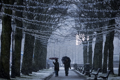 amsterdam-mensen-wandelen-door-een-winterse-bui-met-een-paraplu-buien-met-hagel-en-natte-sneeuw-trekken-over-nederland-robin-van-lonkhuijsen-anp