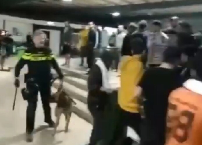 Videostill van een agent met hond in de noodopvang voor asielzoekers in Zuidbroek.