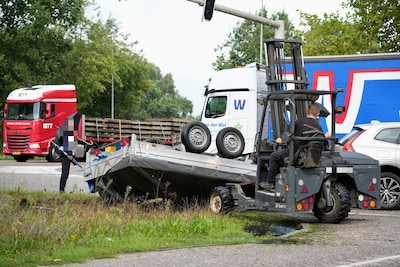 Aanhanger vliegt over de kop in Dongen, vrachtwagenchauffeur schiet te hulp