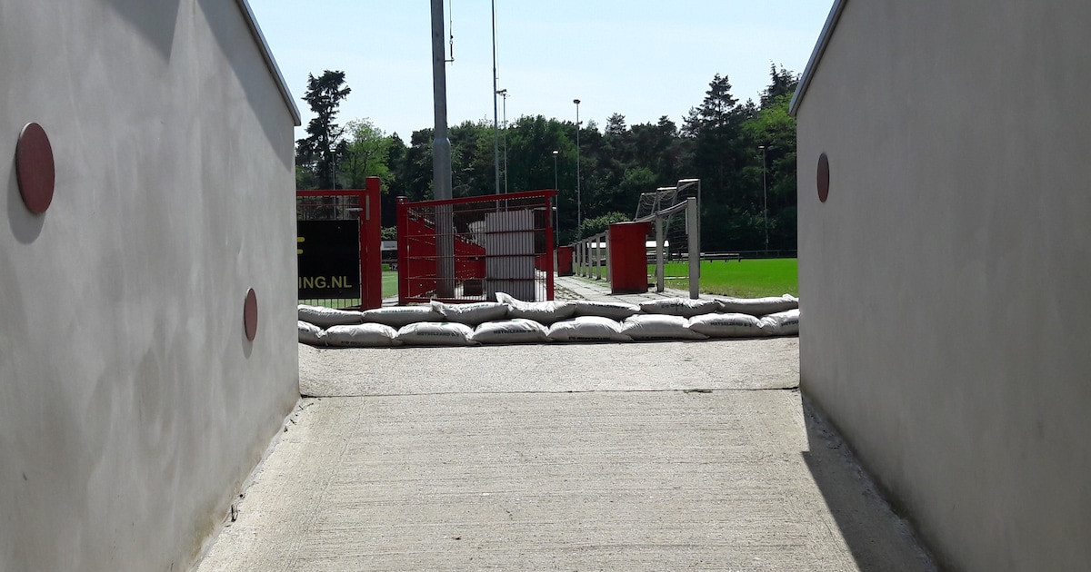 Zandzakken voor de deur na overstroomde kleedkamers in Alverna