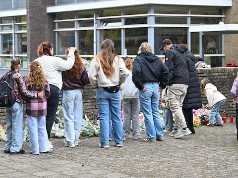 Mensen komen samen en leggen bloemen neer bij de poort van basisschool De Warende. 