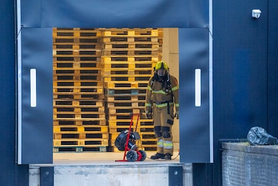 Container vat vlam bij bedrijf in Oss, brandweer blust met handblusser