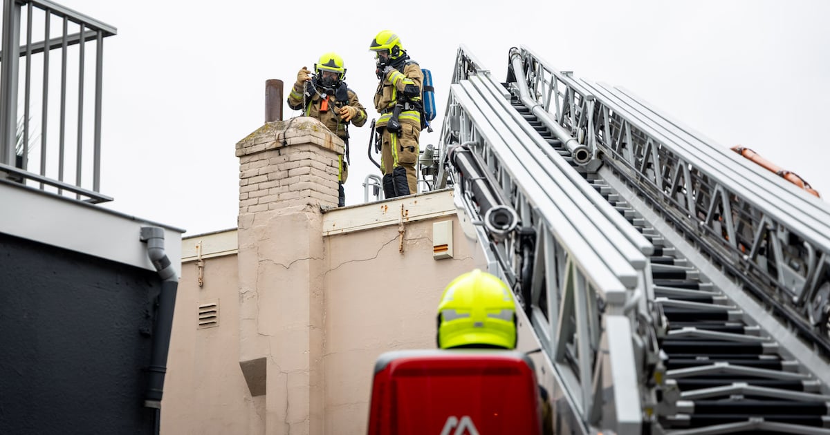 Brandweer veegt schoorsteen in de Brugstraat in Zandvoort na brand
