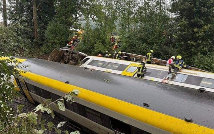 Reddingswerkers zoeken naar passagiers in de ontspoorde trein.