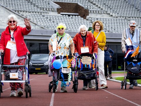 Deelnemers aan de Nationale Rollatorloop in het Olympisch Stadion. Het evenement is bedoeld om het fysieke en mentale welzijn van ouderen te bevorderen.