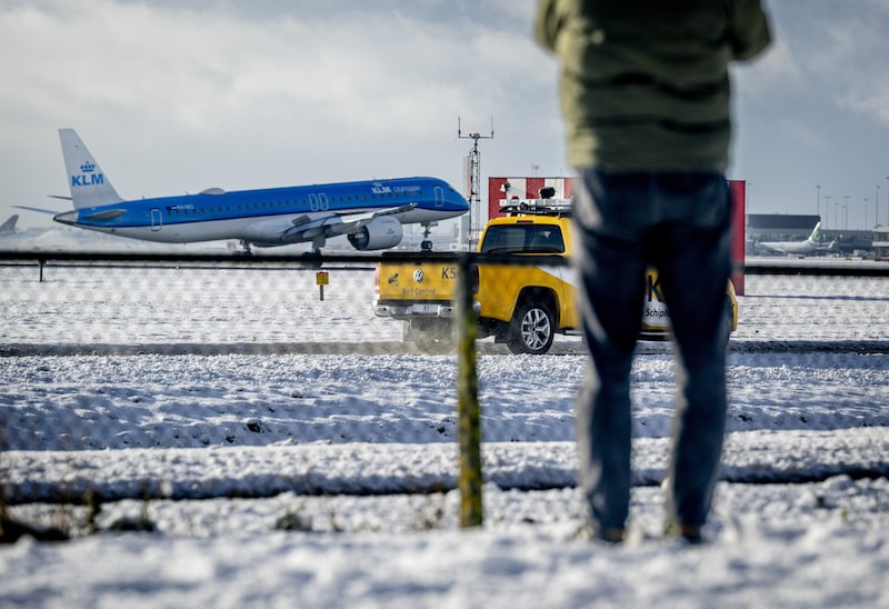 Een vliegtuig landt in de sneeuw op luchthaven Schiphol. 