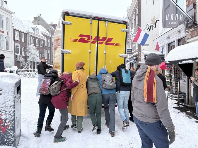 DHL-bussen zitten vast in sneeuw op Oudegracht, maar omstanders duwen ...