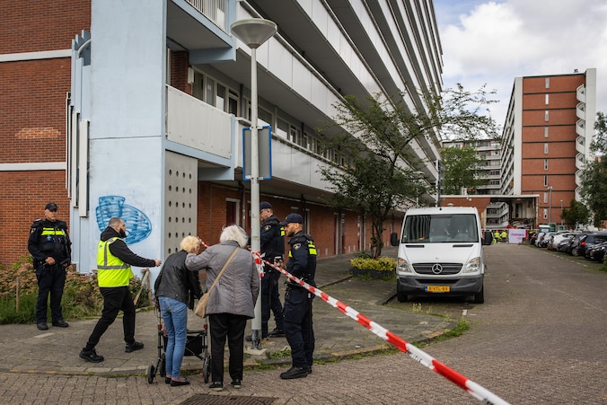 Buurtbewoners bij de flat. Op de achtergrond de sportschool Onna 365.