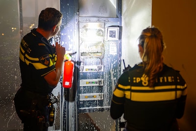 Vlammen bij portiek van flatcomplex, mogelijk brandend voorwerp in brievenbus